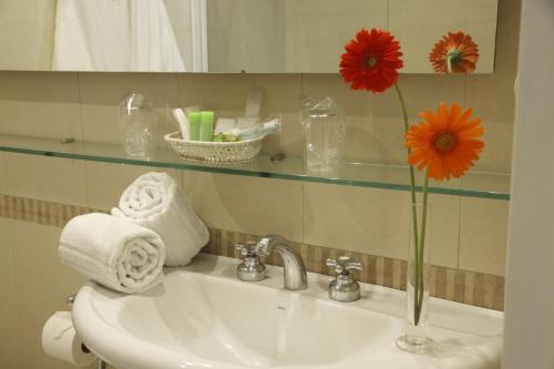 un lavabo con un jarrón con una flor. en El Conquistador Hotel en Buenos Aires