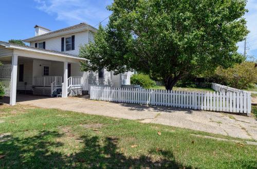 a white fence in front of a house with a tree at Outer Banks Motel - Village Accommodations in Buxton