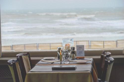 einen Tisch in einem Restaurant mit Meerblick in der Unterkunft Strandhotel De Haan in De Haan