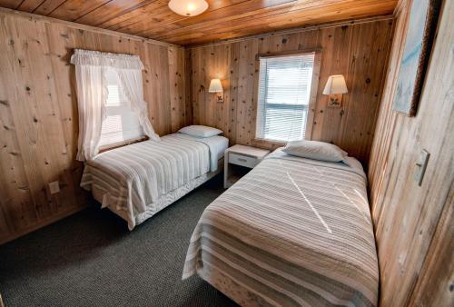 a bedroom with two beds in a wooden cabin at Outer Banks Motel - Village Accommodations in Buxton