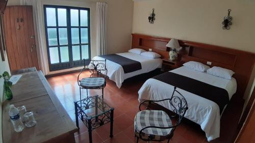 a hotel room with two beds and a table at Hotel Posada Santa Bertha in Texcoco de Mora