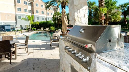 a outdoor kitchen with a grill and a pool at Staybridge Suites Houston-NASA Clear Lake by IHG in Webster