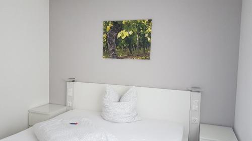 a bedroom with a white bed with a picture on the wall at Gästezimmer Fuchs in Ramsthal