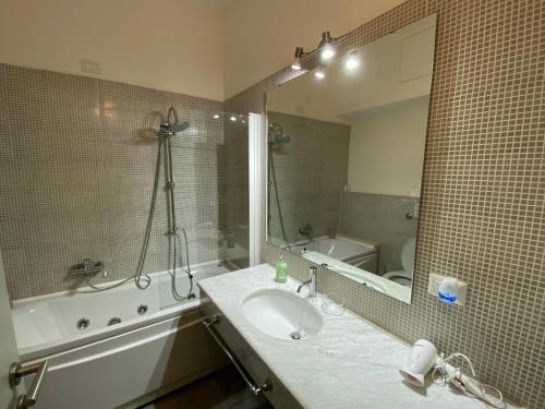 een badkamer met een wastafel, een bad en een spiegel bij NEW Bcomfort in Cagliari