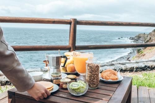 a table with food and a view of the ocean at Abrigo da Cascata - Casas de Campo - São Jorge in Calheta