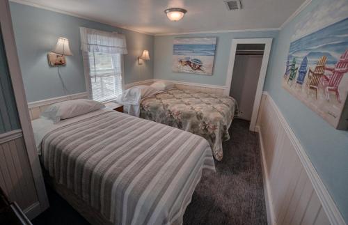 a small bedroom with two beds and a window at Outer Banks Motel - Village Accommodations in Buxton