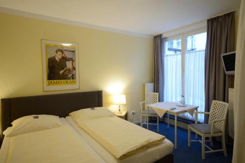 a hotel room with a bed and a table and a window at ALPHA Hotel Garni in Hamburg