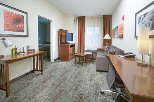 a hotel room with a desk and a living room at Staybridge Suites Augusta by IHG in Augusta