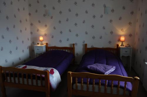 two beds in a bedroom with two lamps on the wall at Le Champ in Le Clerjus