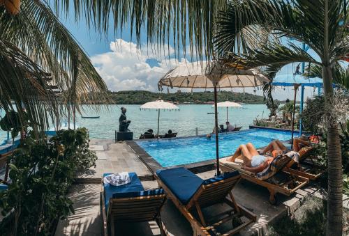 two people laying in chairs next to a swimming pool at Aurora Beach View in Nusa Lembongan