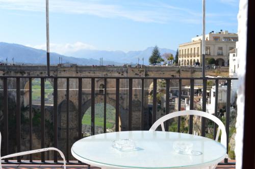 a table and chairs on a balcony with a view of the city at Casa Duende del Tajo in Ronda
