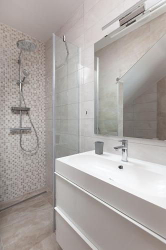 a white bathroom with a sink and a shower at Apartments Galic in Podgora