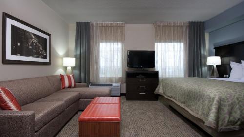 a hotel room with a bed and a couch and a television at Staybridge Suites Buffalo-Amherst by IHG in Amherst