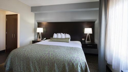 a hotel room with a large bed with two lamps at Staybridge Suites Buffalo-Amherst by IHG in Amherst