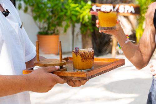 a group of people holding drinks on a wooden tray at The Beach Tulum in Tulum