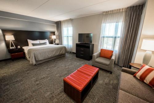 a hotel room with a bed and a chair at Staybridge Suites Albany Wolf Rd-Colonie Center by IHG in Albany