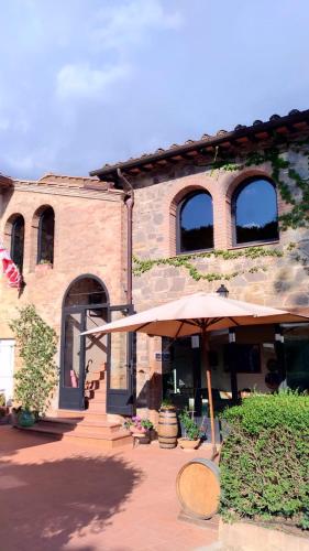 a building with an umbrella in front of it at Podere San Quirico in Castelnuovo Berardenga