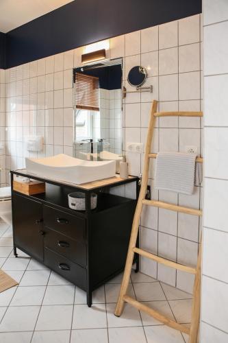 a bathroom with a sink and a wooden ladder at Sleepwell Apartment - Klostersuite in Leipzig