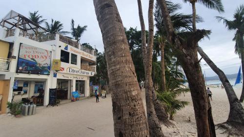 a palm tree next to a beach with buildings at DiveGurus Boracay Beach Resort in Boracay