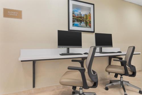 a desk with two monitors and two chairs at Candlewood Suites - Charlotte - Arrowood by IHG in Charlotte