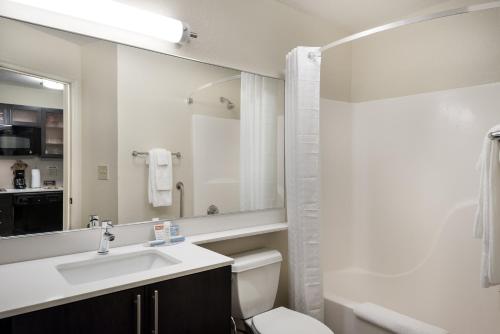 a bathroom with a sink and a toilet and a mirror at Candlewood Suites - Charlotte - Arrowood by IHG in Charlotte