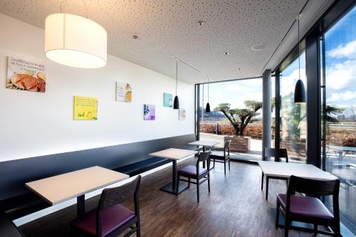 a restaurant with tables and chairs and large windows at Motel Rheinfels Park in Stein