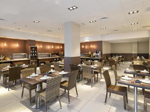 una sala da pranzo con tavoli e sedie e un ristorante di Hotel Guadalmedina a Málaga