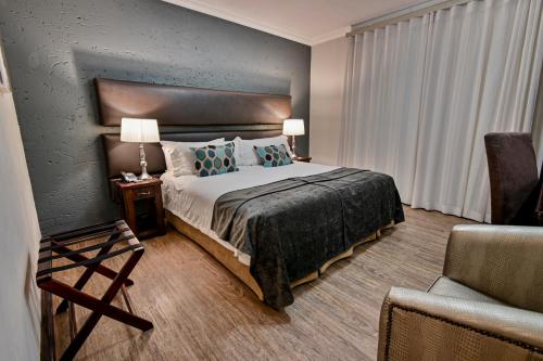 a hotel room with a bed and a chair at Villa Bali Luxury Guesthouse in Bloemfontein