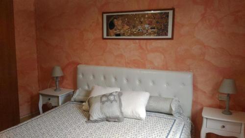 a bedroom with a white bed with two tables and two lamps at Alloggio Castello Tesino in Castello Tesino