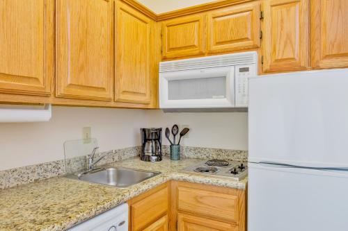 a kitchen with wooden cabinets and a sink and a refrigerator at Staybridge Suites - Brownsville by IHG in Brownsville