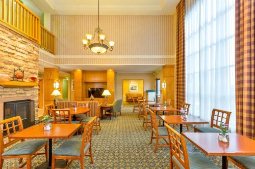 a restaurant with wooden tables and chairs and a fireplace at Staybridge Suites - Brownsville by IHG in Brownsville