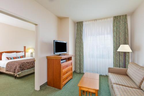 a hotel room with a bed and a flat screen tv at Staybridge Suites - Brownsville by IHG in Brownsville