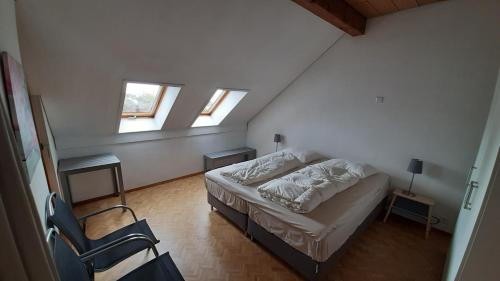 a small bedroom with a bed and two windows at La Petite Fleur in Enges