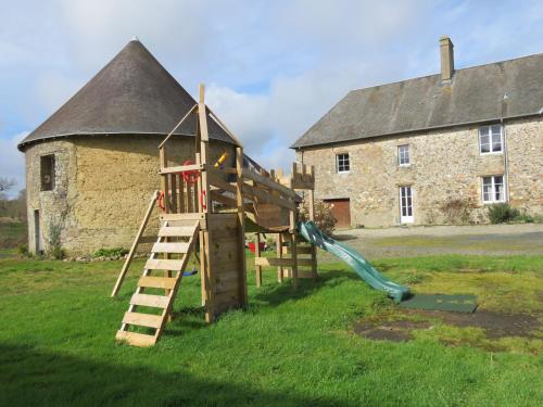 a playground in front of an old stone building at Domaine La Synchronicité - Gîte et Chambres d'Hôtes in Vaudrimesnil
