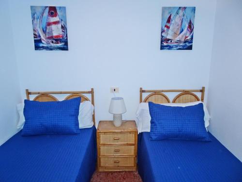 two beds in a room with blue pillows and a lamp at ROMA XII - Apartamento Familiar in Playa de Gandia