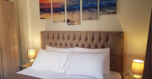 ein Bett mit weißen Kissen und Gemälden an der Wand in der Unterkunft City's Center Lux. Apt.Up 4 persons and BBQ in Kavala