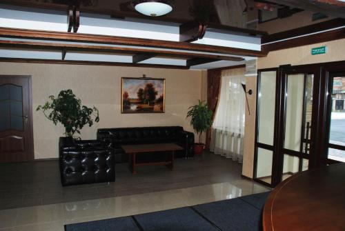 een woonkamer met een zwarte bank en een tafel bij Shato Paradis Hotel in Irpin'