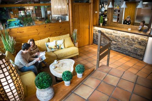 two people sitting on a couch in a living room at Hotel Restaurant Les Brases in Sort