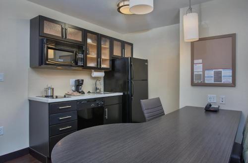 a kitchen with a table and a black refrigerator at Candlewood Suites Bowling Green by IHG in Bowling Green
