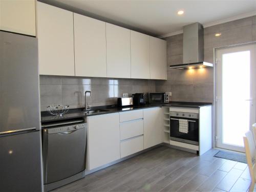 a kitchen with white cabinets and a stove at Porta40 - Vacation House in Bombarral