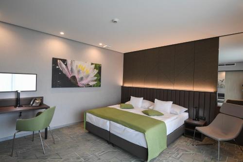 a bedroom with a bed and a desk and chairs at Hunguest Hotel Sóstó in Nyíregyháza