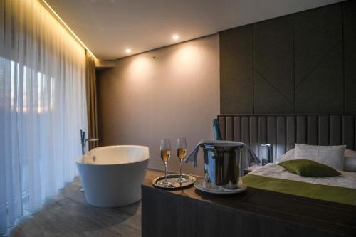 un bagno con vasca, letto, vasca e bicchieri di Hunguest Hotel Sóstó a Nyíregyháza