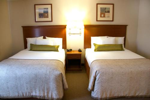 a hotel room with two beds and a lamp at Candlewood Suites Champaign-Urbana University Area by IHG in Champaign