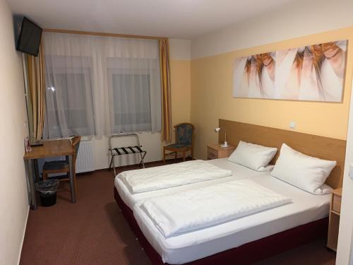 Schlafzimmer mit einem großen weißen Bett und einem Schreibtisch in der Unterkunft Hotel National in Koblenz