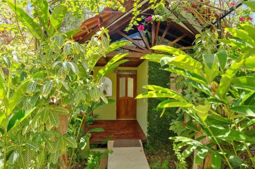 a green house with a wooden door in a garden at Anamaya Resort in Montezuma