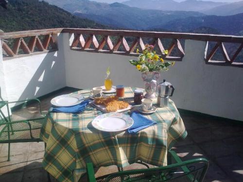 a table with plates of food on a balcony at Casa El Olivo by CasaTuristica in Benalauría