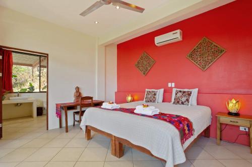 a bedroom with a large bed with a red wall at Anamaya Resort in Montezuma