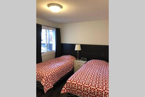 two beds in a hotel room with red and white sheets at Mountain Edge Ski-in Ski-out Condo in Kimberley