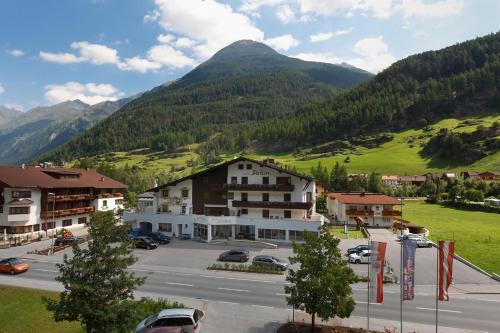a town in the mountains with cars parked in a parking lot at Haus Anton Sölden - Apartments & Zimmer in Sölden