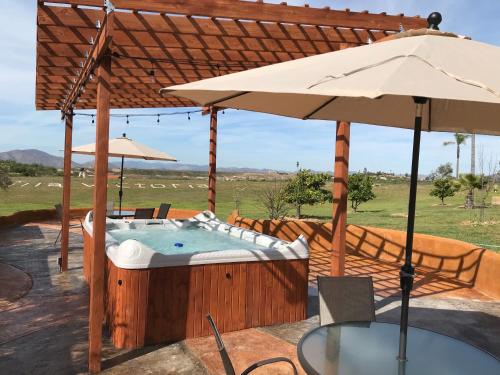 a hot tub with a table and an umbrella at Villa Victoria in Valle de Guadalupe
